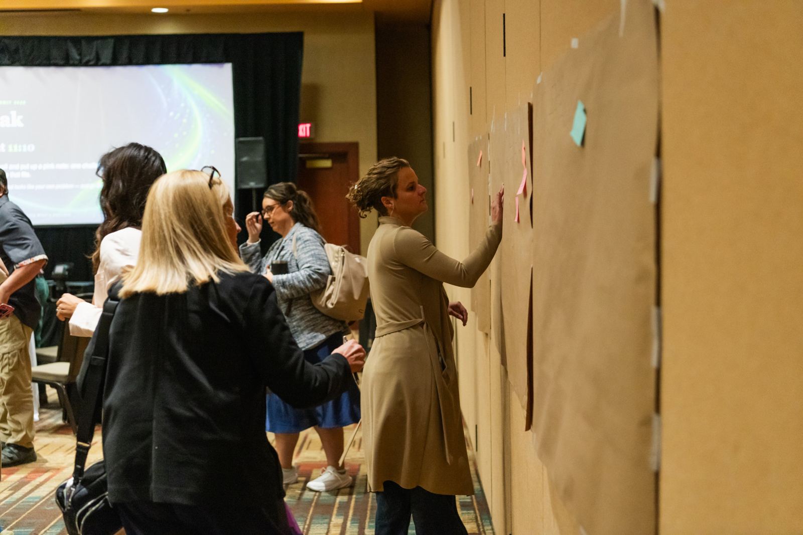 Attendees reading and posting notes on the wall during a break
